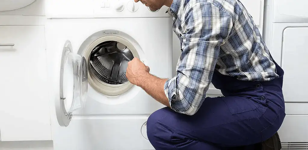 Handyman inspecting a dryer drum and internal parts for repair in Rochester, NY