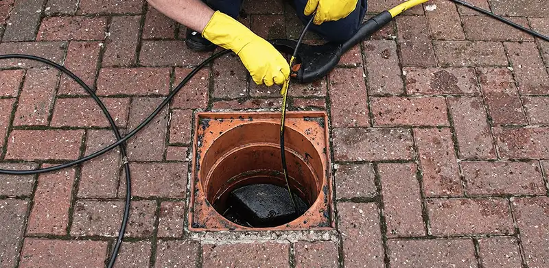 Drain cleaning technician using a drain snake to clear a clogged drain in Rochester, NY