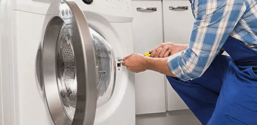 Handyman repairing a clothes dryer and checking electrical connections in Rochester, NY
