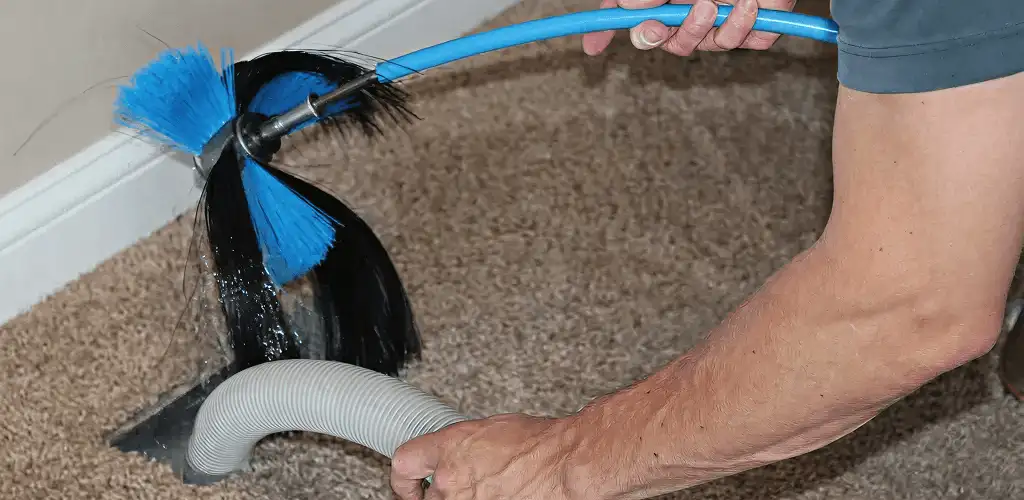 Dryer vent cleaning technician brushing lint from a vent line in Rochester, NY