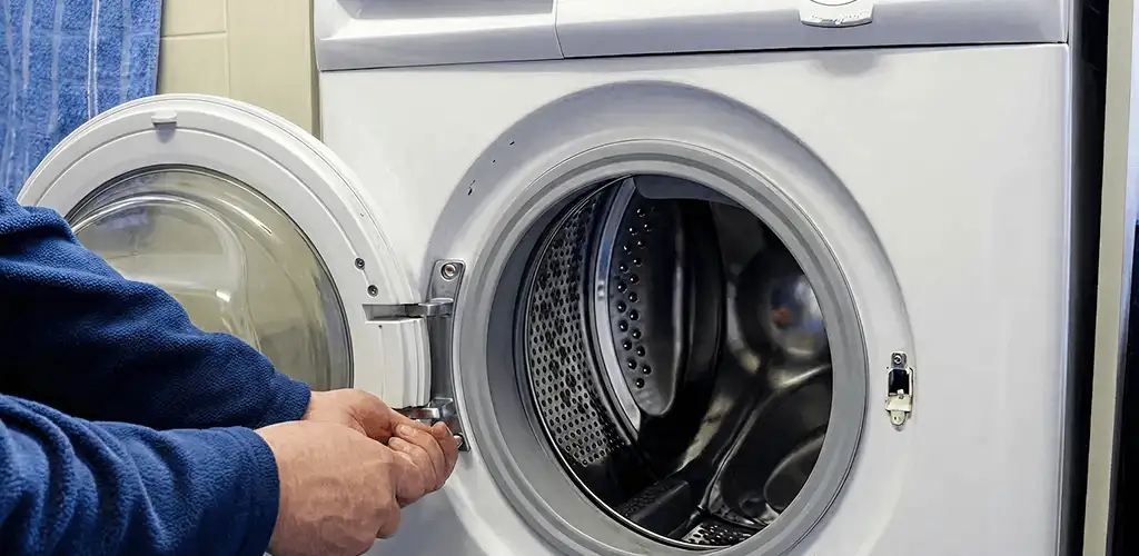 Washing machine repair handyman checking a front-load washer door and latch in Rochester, NY