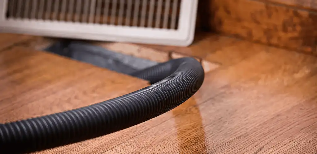 Air duct cleaning hose inserted into a floor vent for ductwork cleaning in Rochester, NY