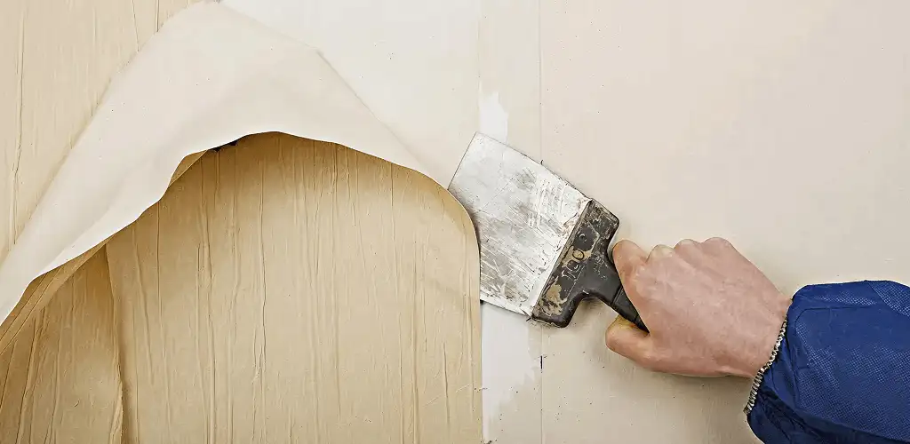 Handyman removing wallpaper with a scraper for wall preparation in Rochester, NY