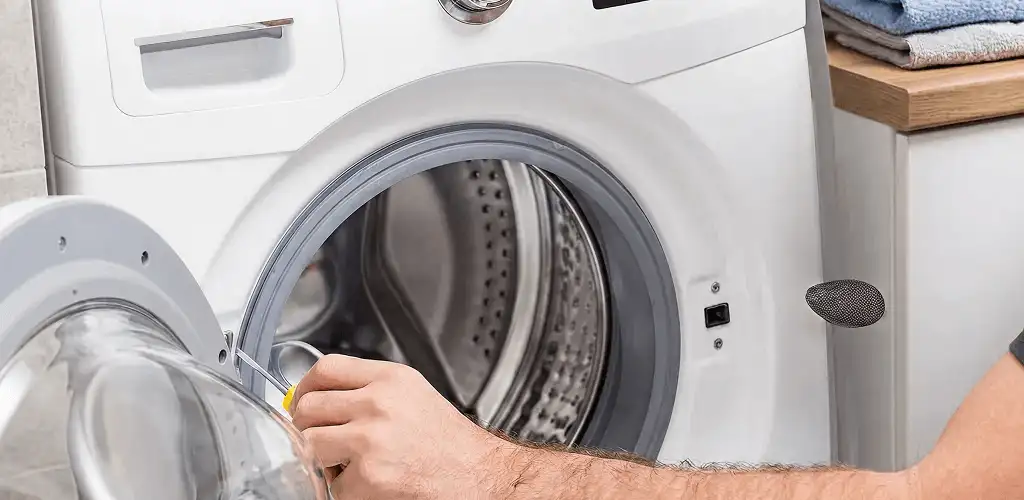 Handyman repairing a front-load washing machine and inspecting the drum in Rochester, NY