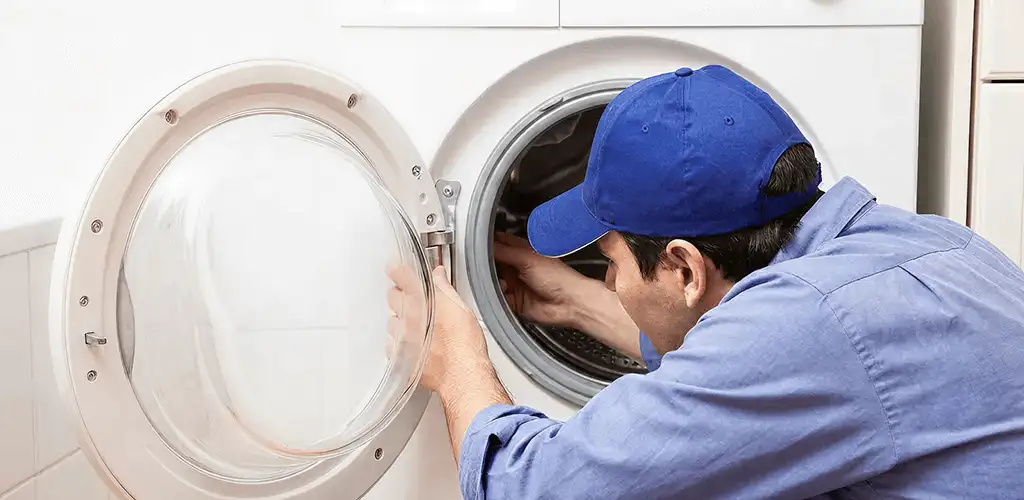 Washing machine repair handyman inspecting a front-load washer drum in Rochester, NY