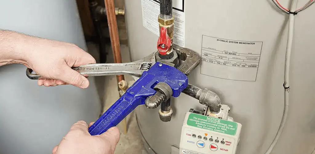 Water heater repair technician tightening the shutoff valve and supply line in Rochester, NY